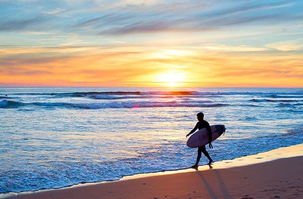 Surfer with board walking along the beach in the sunset, Algarve